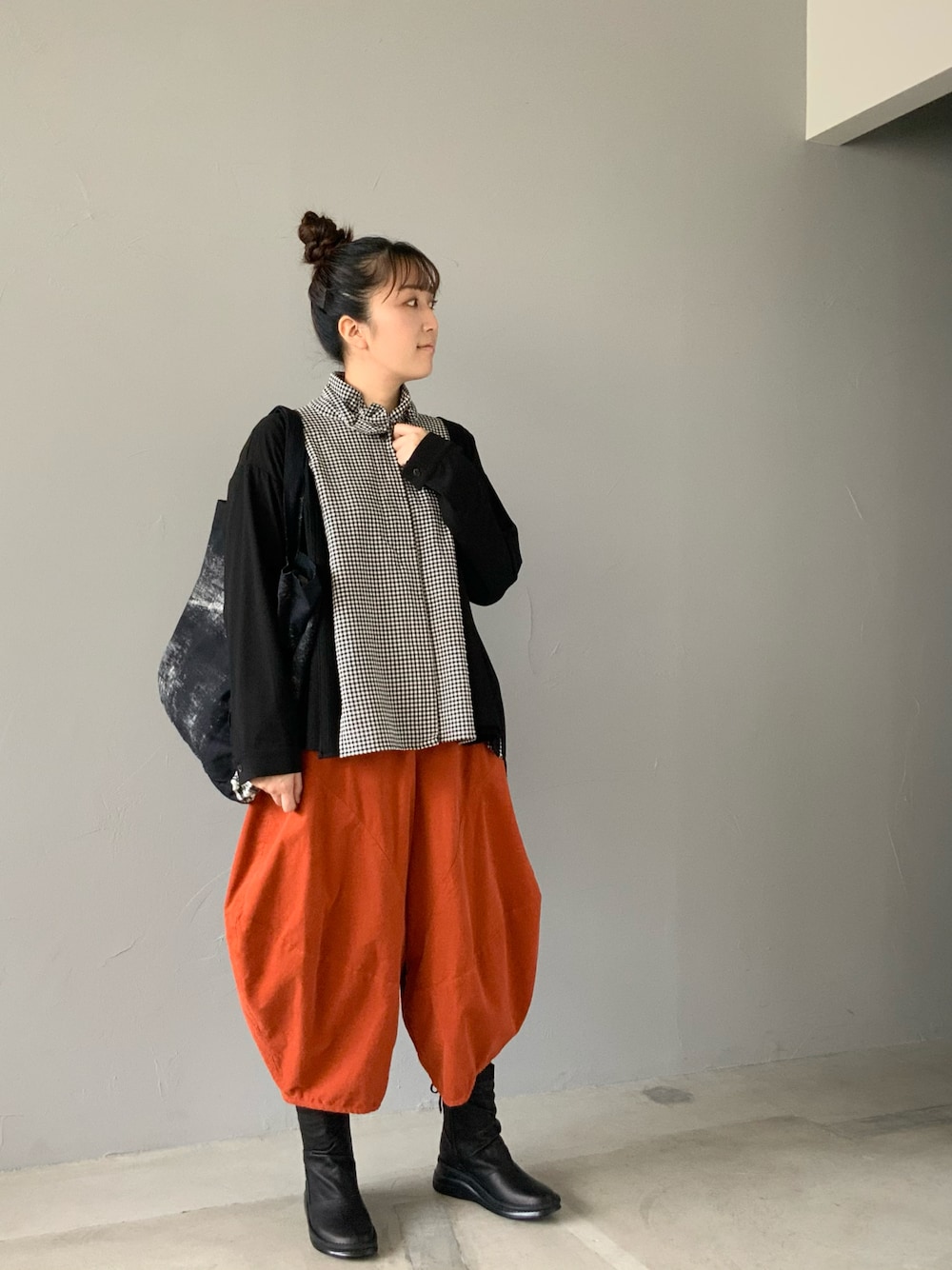 ブラック系のシャツ/ブラウス、ブラック系のトートバッグ、オレンジ系のパンツを着用したレディースの秋コーディネートの1枚目の写真