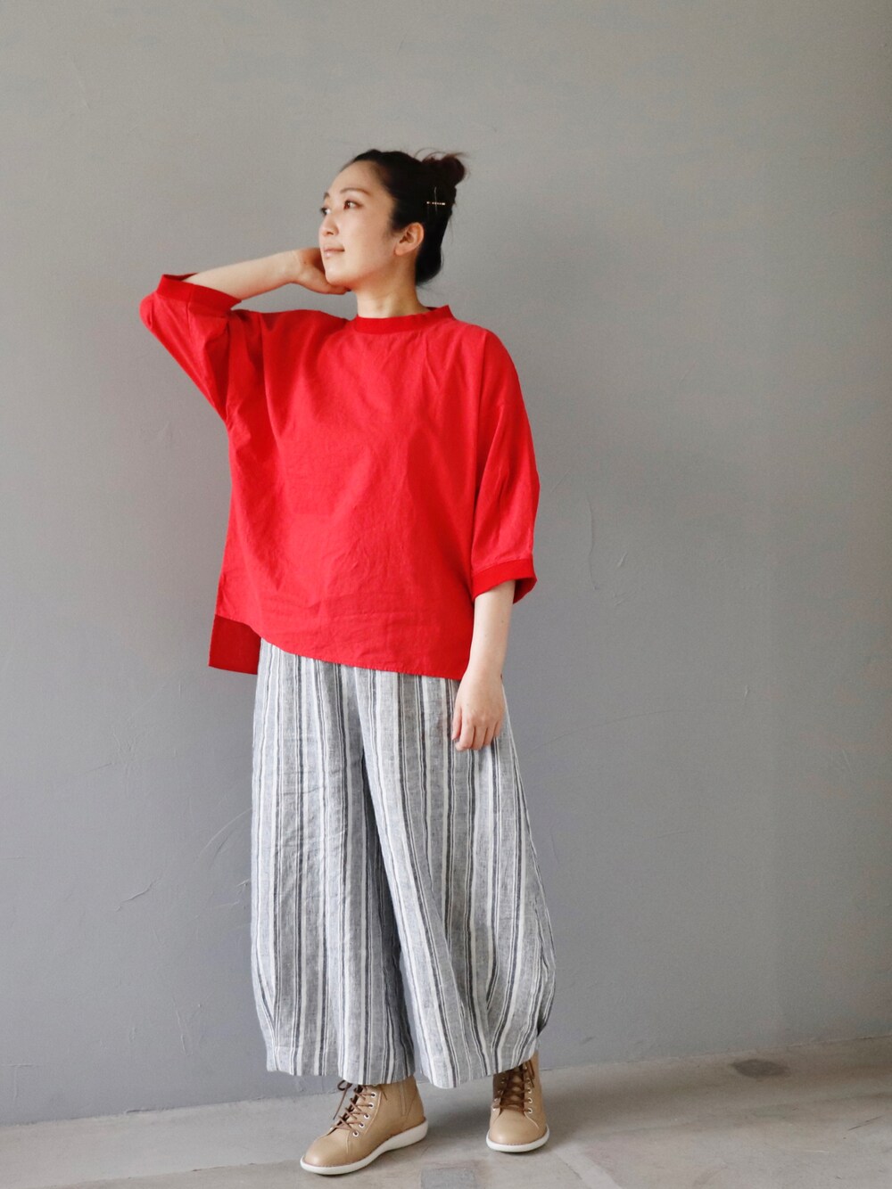 レッド系のトップス、グレー系のパンツ、ベージュ系のシューズを着用したレディースの春コーディネートの1枚目の写真