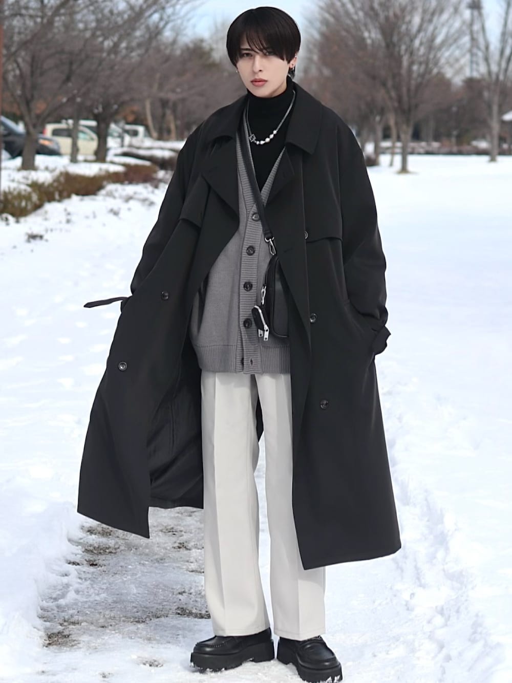 ブラック系のトレンチコート、グレー系のカーディガン/ボレロ、ブラック系のショルダーバッグを着用したメンズの冬コーディネートの1枚目の写真