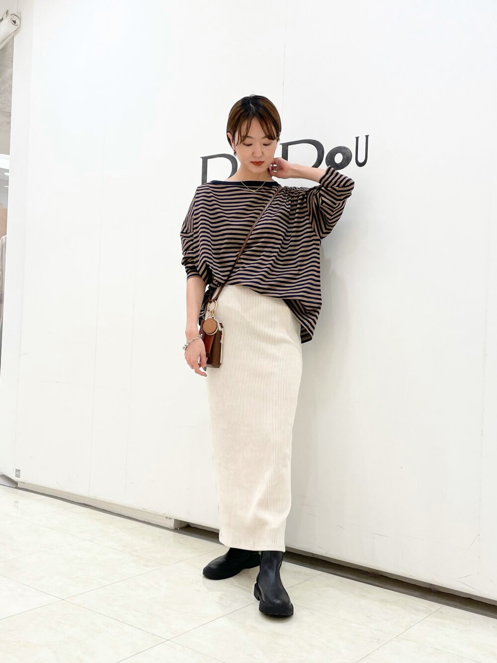 イエロー系のTシャツ/カットソー、グレー系のスカート、ブラウン系のショルダーバッグを着用したレディースの秋コーディネートの1枚目の写真