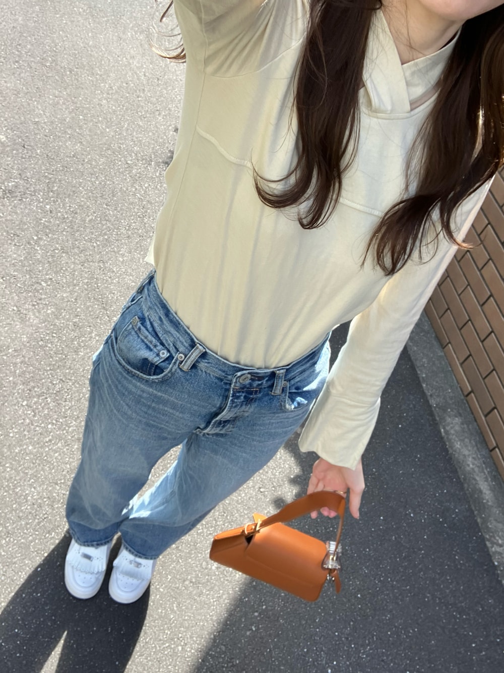 ホワイト系のスニーカー、ブルー系のデニムパンツ、ベージュ系のTシャツ/カットソーを着用したレディースの秋コーディネートの1枚目の写真