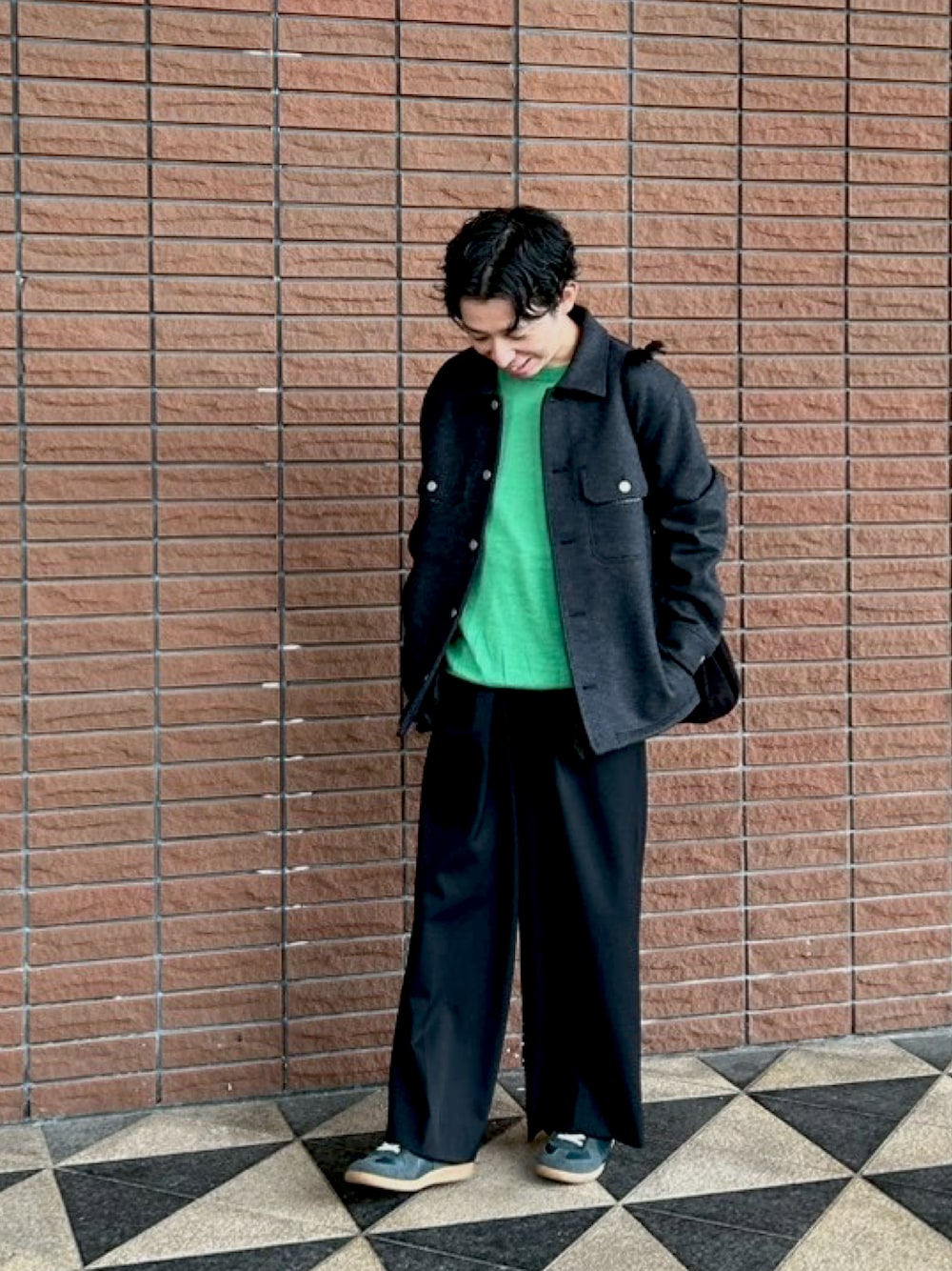 ブラック系のスニーカー、グリーン系のニット/セーター、グレー系のジャケット/アウターを着用したメンズの秋コーディネートの1枚目の写真