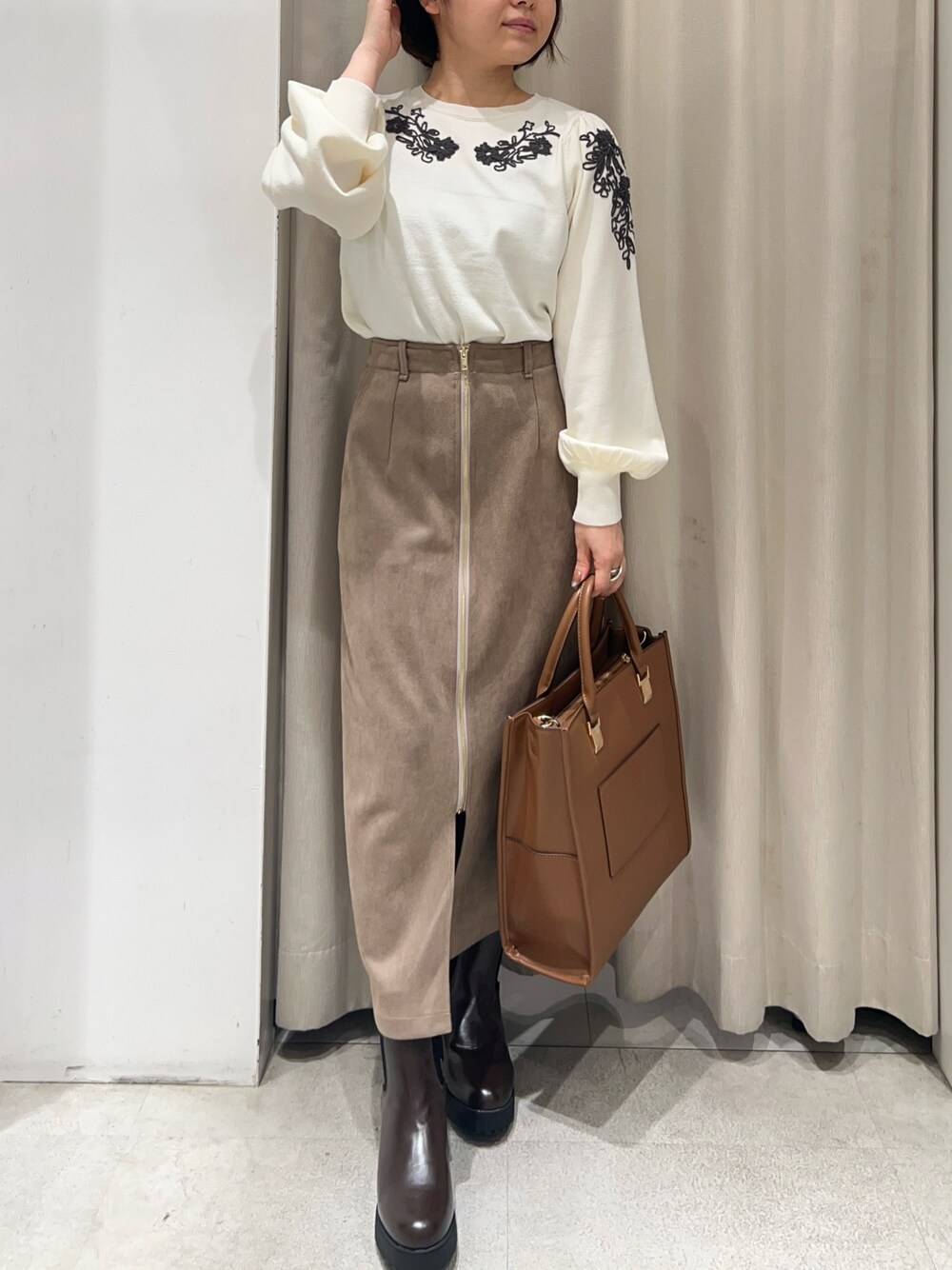 ホワイト系のニット/セーター、ブラウン系のバッグ、ベージュ系のスカートを着用したレディースの秋コーディネートの1枚目の写真