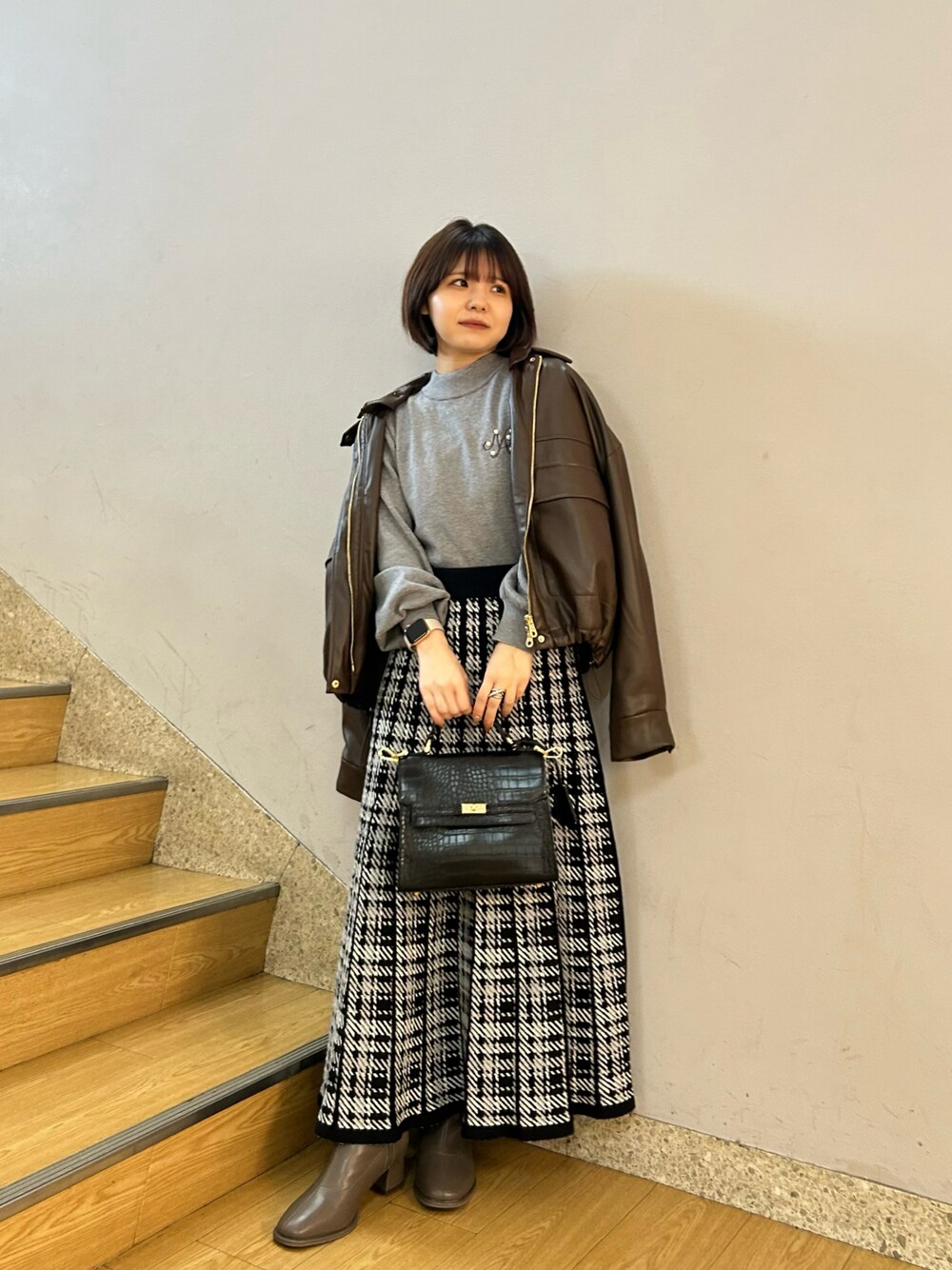 ブラウン系のブルゾン、ブラック系のスカートを着用したレディースの秋コーディネートの1枚目の写真