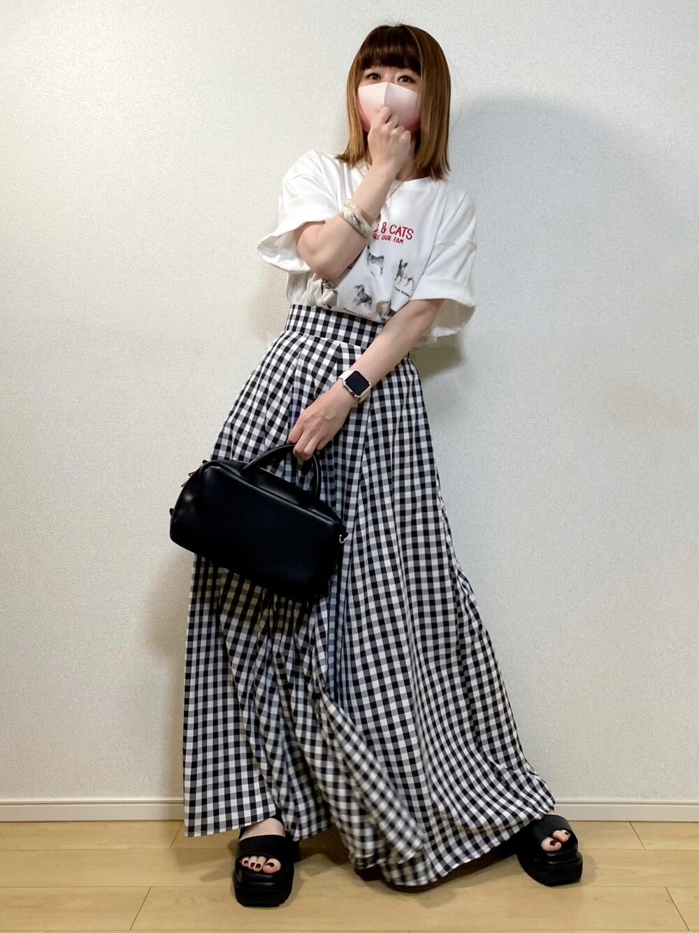 ブラック系のスカート、ホワイト系のTシャツ/カットソー、ブラック系のボストンバッグを着用したレディースの春コーディネートの1枚目の写真