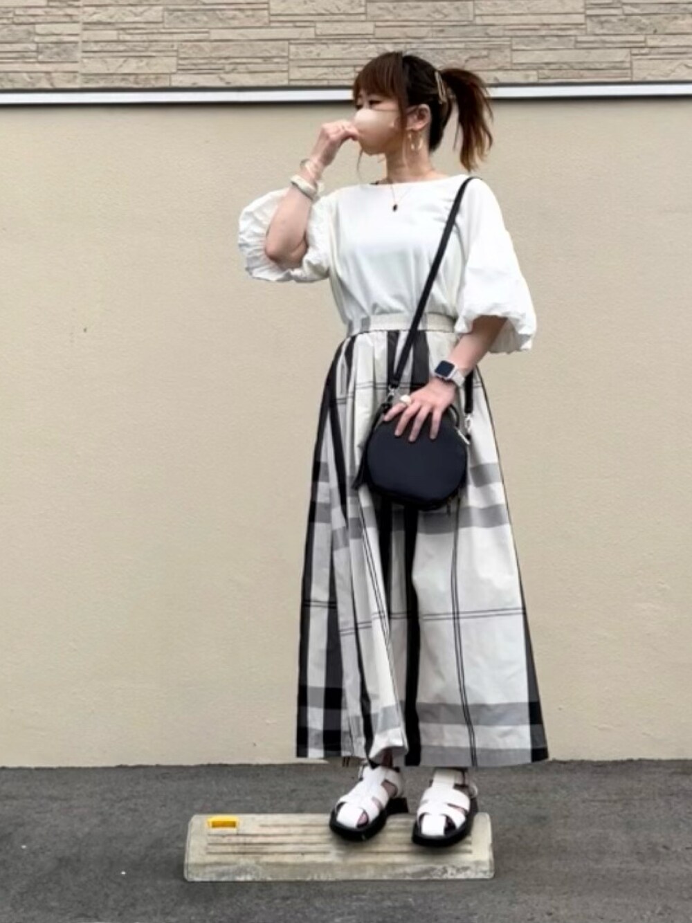ホワイト系のスカート、ブラック系のトップス、ホワイト系のサンダルを着用したレディースの夏コーディネートの1枚目の写真