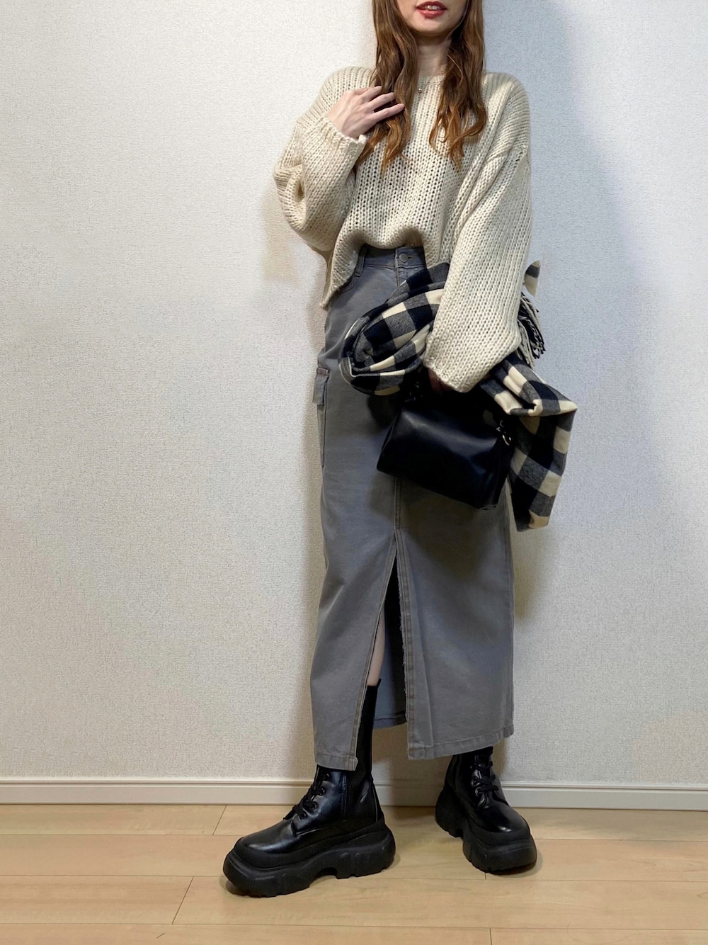 ホワイト系のニット/セーター、ブラック系のハンドバッグ、ブラック系のブーツを着用したレディースの冬コーディネートの1枚目の写真