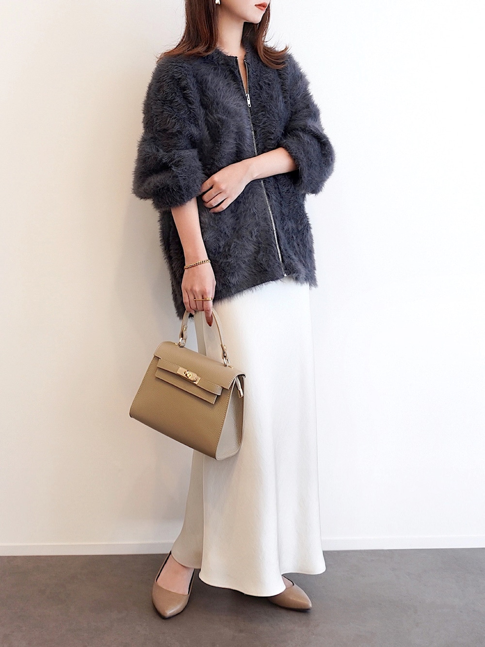 グレー系のカーディガン/ボレロ、ホワイト系のスカート、その他のパンプスを着用したレディースの秋コーディネートの1枚目の写真