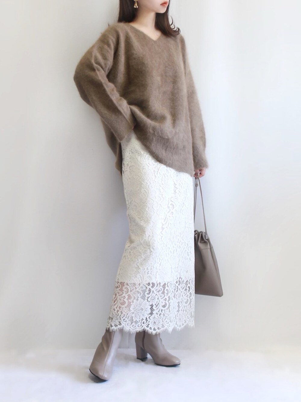 ベージュ系のブーツ、ブラウン系のニット/セーター、ホワイト系のスカートを着用したレディースの秋コーディネートの1枚目の写真