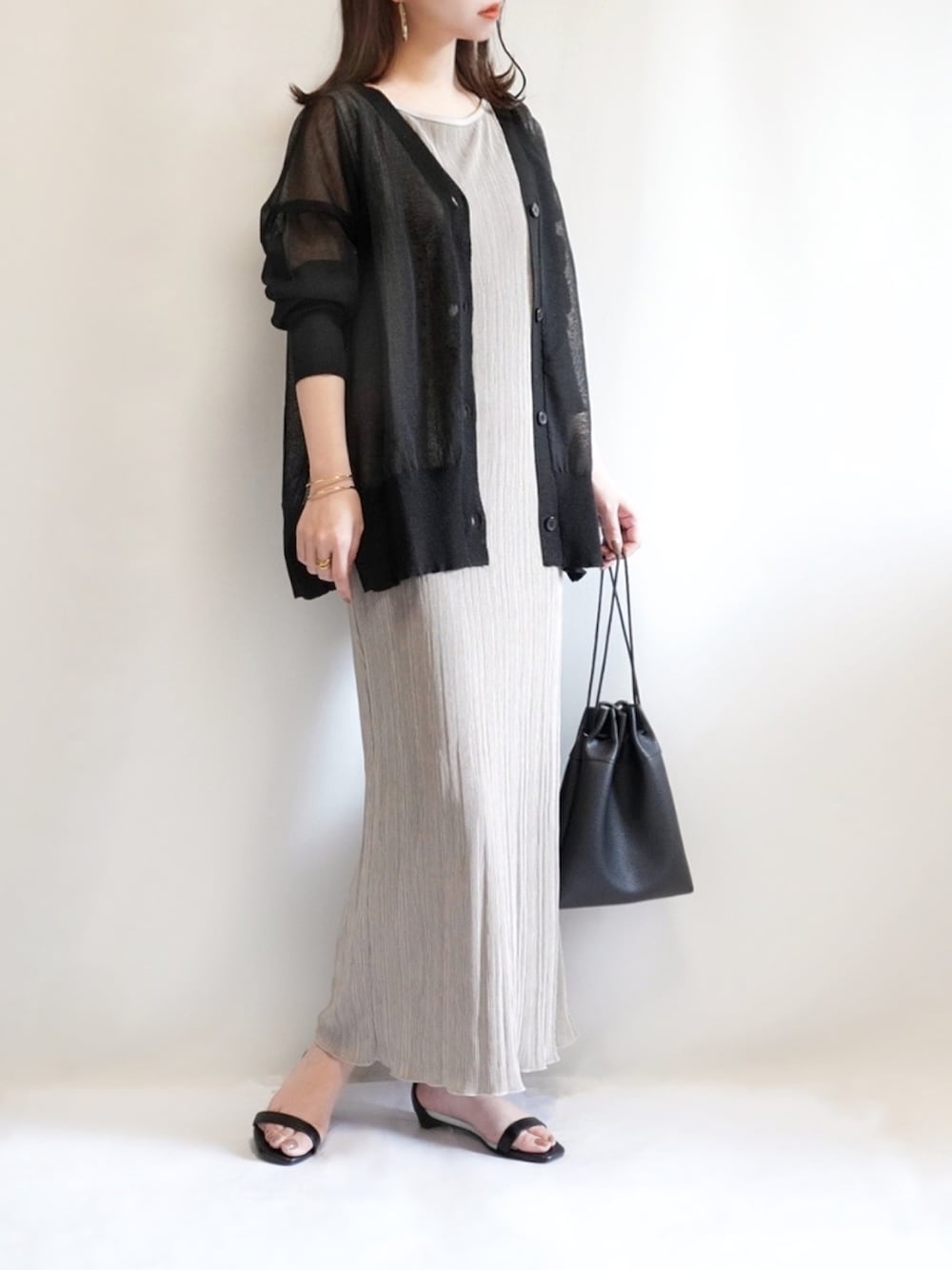 ブラック系のカーディガン/ボレロ、ベージュ系のワンピース、ブラック系のサンダルを着用したレディースの春コーディネートの1枚目の写真