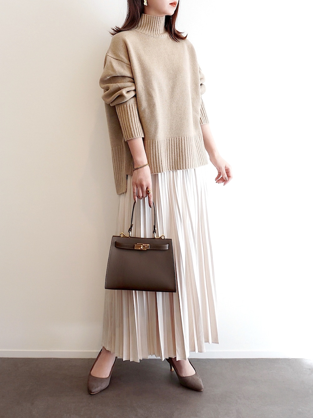 ベージュ系のニット/セーター、ホワイト系のスカート、グレー系のパンプスを着用したレディースの冬コーディネートの1枚目の写真