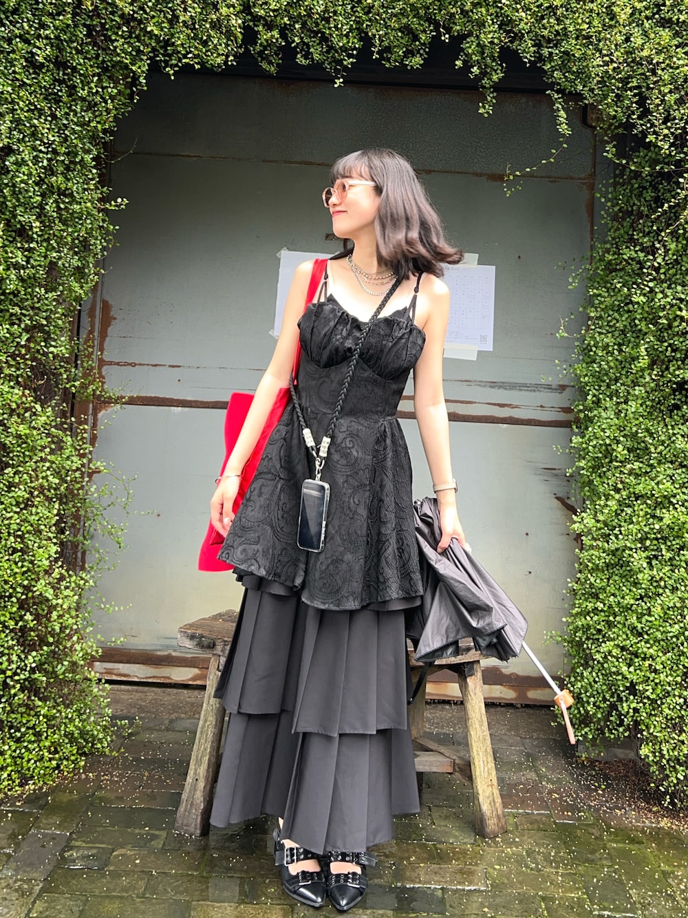 レッド系のトートバッグ、ブラック系のその他トップス、ブラック系のスカートを着用したレディースの夏コーディネートの1枚目の写真