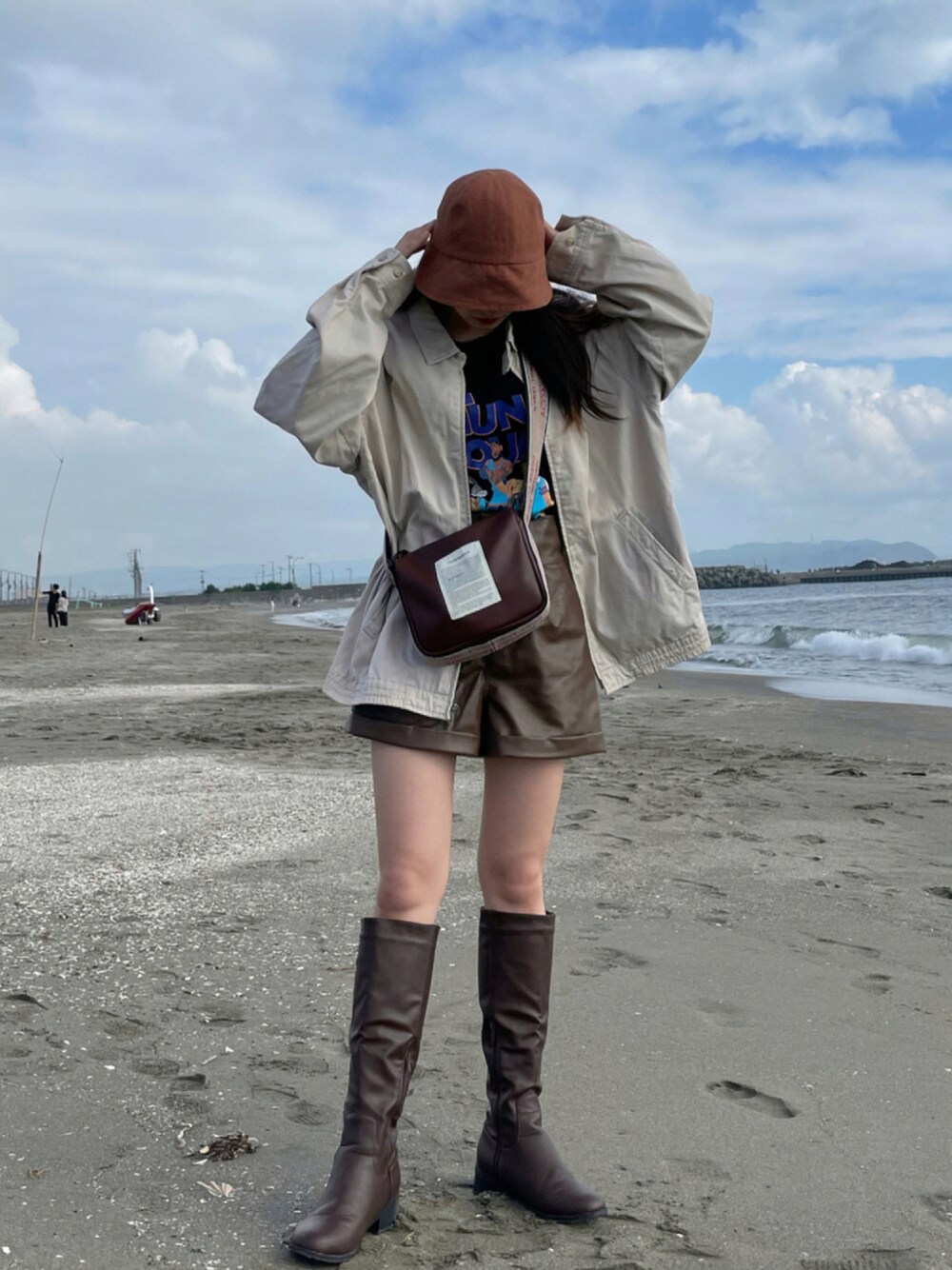 ベージュ系のその他アウター、ブラック系のTシャツ/カットソー、ブラウン系のショルダーバッグを着用したレディースの秋コーディネートの1枚目の写真