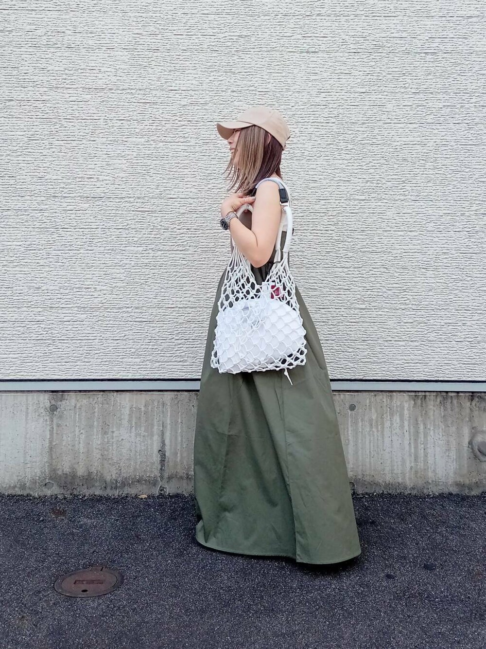 グリーン系のワンピース、ホワイト系のハンドバッグ、ベージュ系のキャップを着用したレディースの夏コーディネートの1枚目の写真