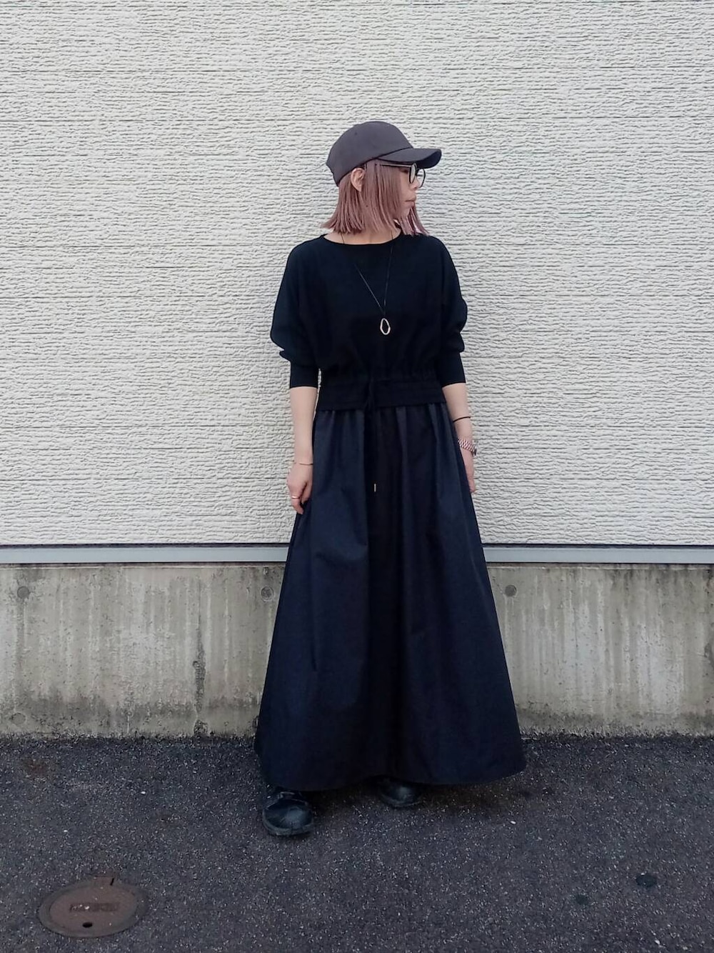 ブラック系のワンピース、グレー系のキャップを着用したレディースの春コーディネートの1枚目の写真