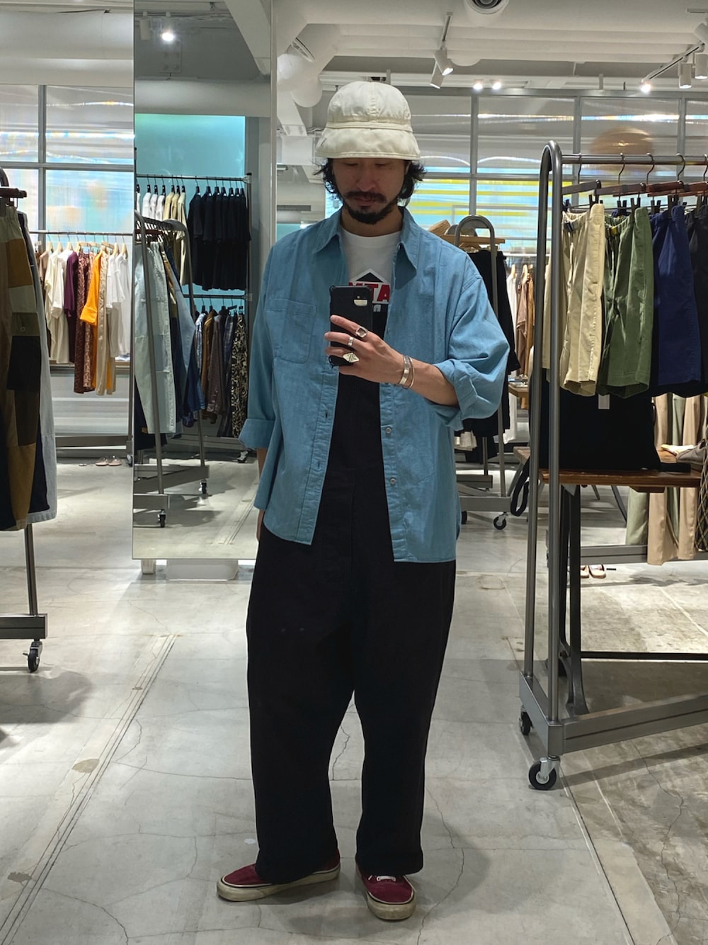 ブルー系のシャツ/ブラウス、ブラック系のサロペット/オーバーオール、レッド系のスニーカーを着用したメンズの秋コーディネートの1枚目の写真