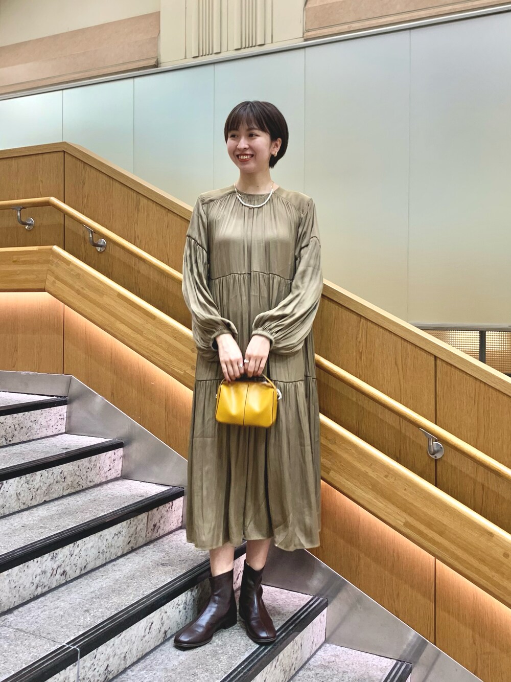 グリーン系のワンピース、イエロー系のショルダーバッグ、ブラウン系のその他シューズを着用したレディースの秋コーディネートの1枚目の写真