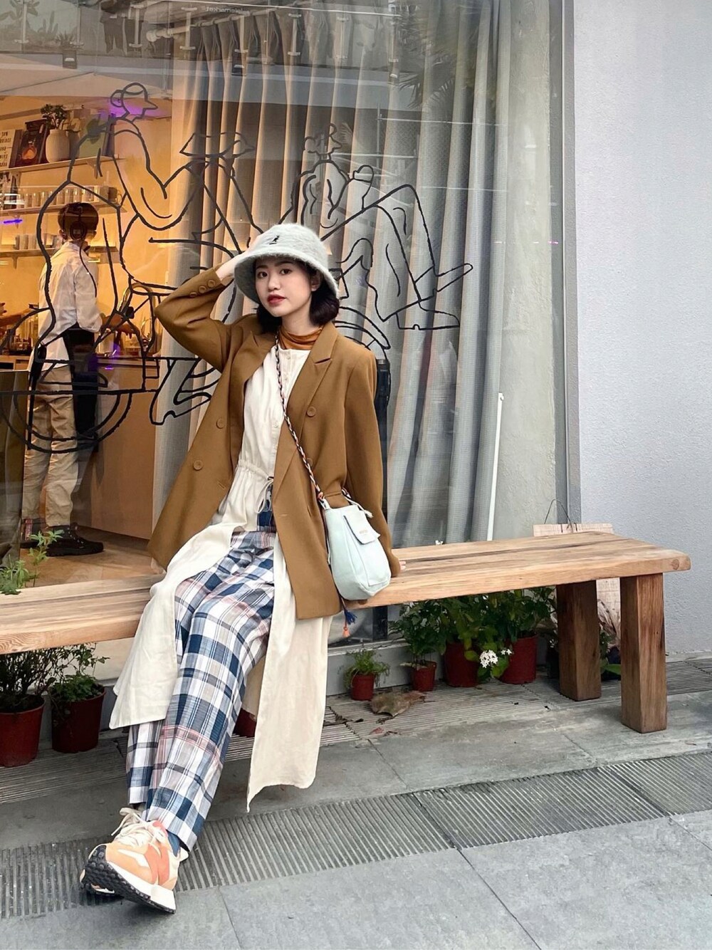 ベージュ系のベスト、ブルー系のショルダーバッグ、オレンジ系のスニーカーを着用したレディースの春コーディネートの1枚目の写真