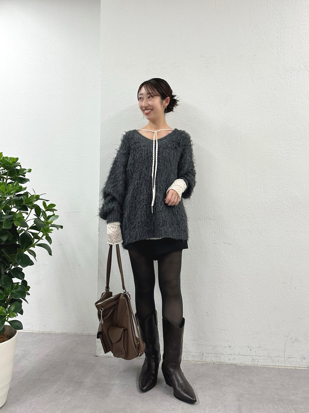 グレー系のニット/セーター、ホワイト系のTシャツ/カットソー、ブラウン系のブーツを着用したレディースの秋コーディネートの1枚目の写真