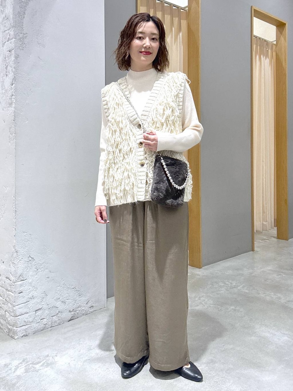 ホワイト系のニット/セーター、ホワイト系のベスト、グレー系のショルダーバッグを着用したレディースの秋コーディネートの1枚目の写真