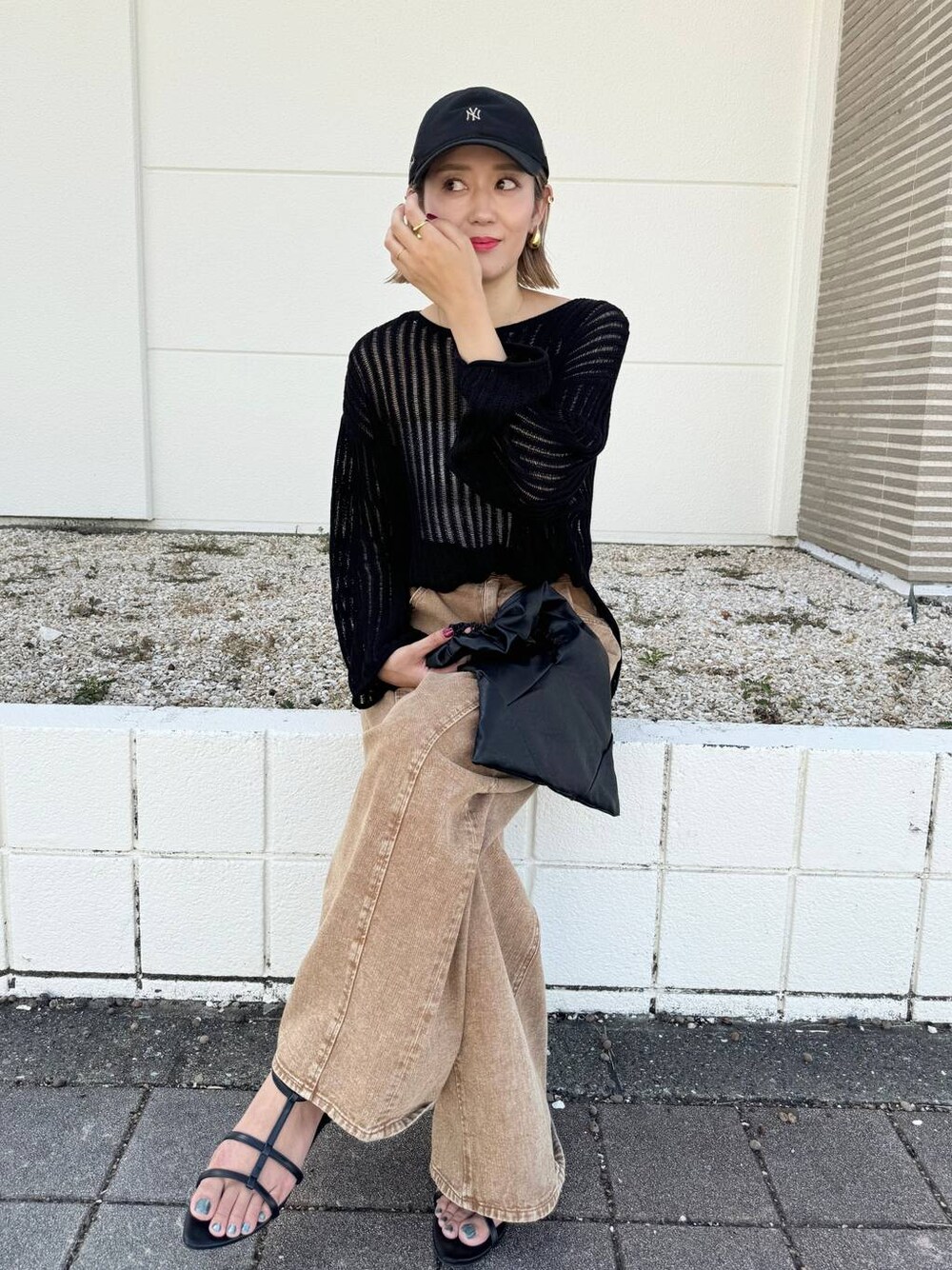 ブラック系のサンダル、ブラウン系のデニムパンツ、ブラック系のニット/セーターを着用したレディースの秋コーディネートの1枚目の写真