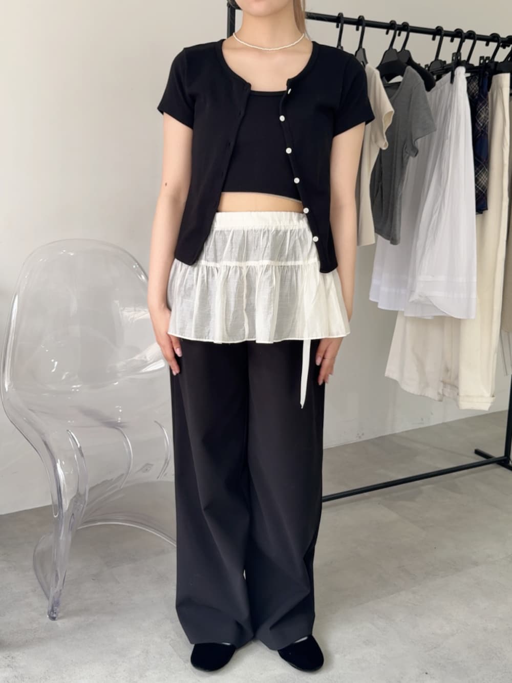 ブラック系のカーディガン/ボレロ、ホワイト系のスカート、ブラック系のスラックスを着用したレディースの夏コーディネートの1枚目の写真