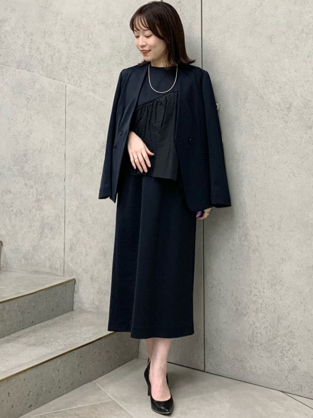 ブルー系のテーラードジャケット、ブルー系のワンピースを着用したレディースの冬コーディネートの1枚目の写真