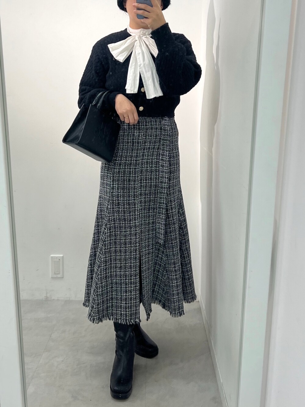 ブラック系のスカート、ブラック系のブーツ、ホワイト系のショルダーバッグを着用したレディースの冬コーディネートの1枚目の写真