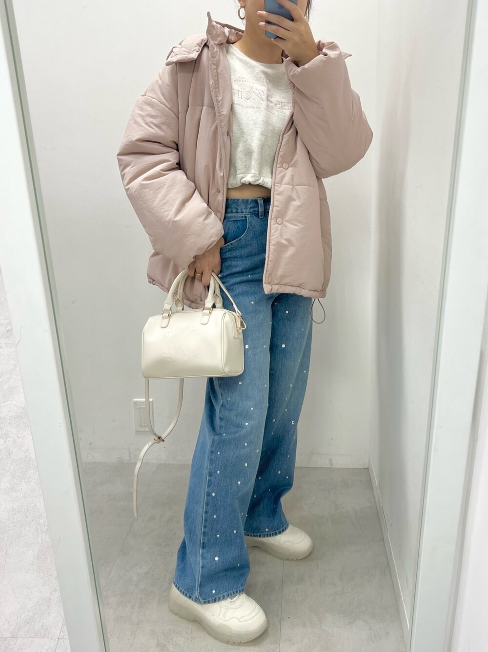 ホワイト系のハンドバッグ、ブルー系のデニムパンツ、ホワイト系のスニーカーを着用したレディースの秋コーディネートの1枚目の写真