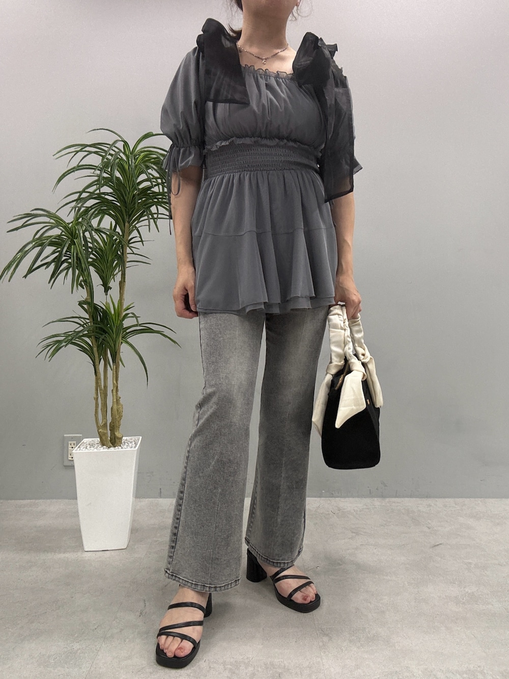 ブラック系のデニムパンツ、ホワイト系のトートバッグ、ブラック系のサンダルを着用したレディースの夏コーディネートの1枚目の写真