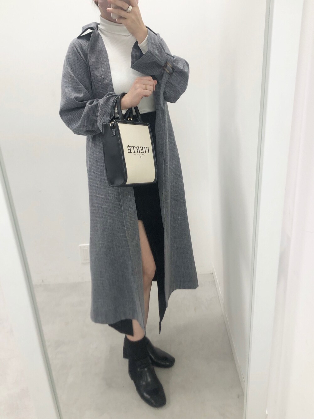 ブルー系のトレンチコート、ブラック系のスカート、ホワイト系のTシャツ/カットソーを着用したレディースの冬コーディネートの1枚目の写真