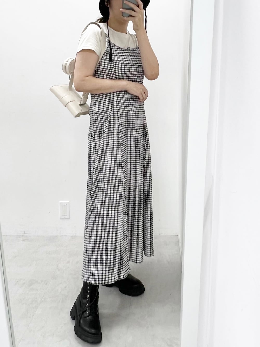 ブラック系のワンピース、ブラック系のブーツ、ホワイト系のショルダーバッグを着用したレディースの夏コーディネートの1枚目の写真