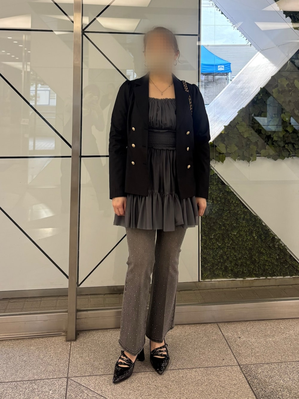 グレー系のワンピース、ブラック系のデニムパンツ、ブラック系のパンプスを着用したレディースの冬コーディネートの1枚目の写真