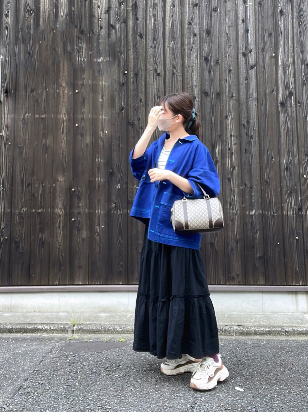 ブルー系のジャケット/アウター、ブラック系のスカート、ブラウン系のボストンバッグを着用したレディースの春コーディネートの1枚目の写真