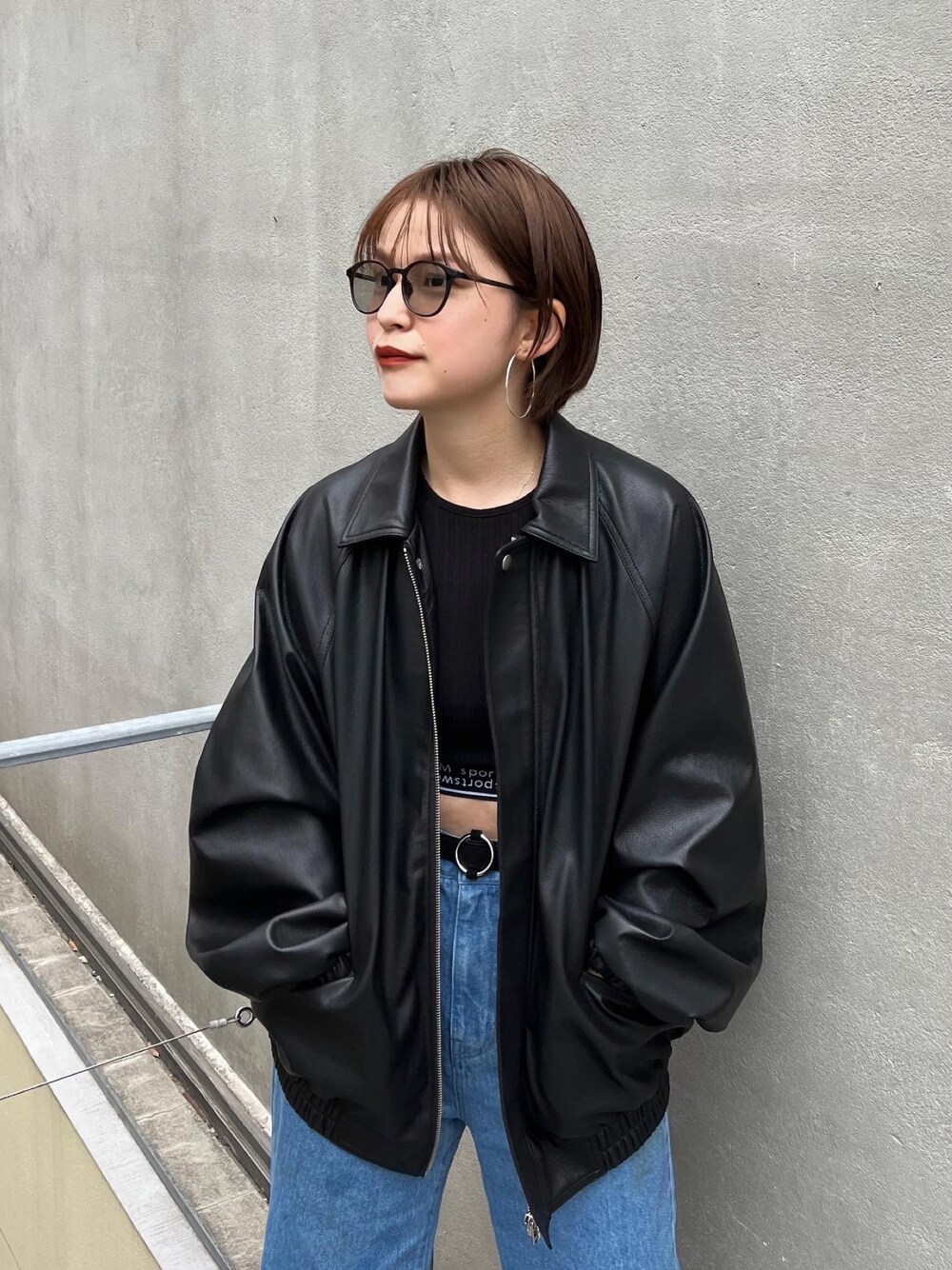 ブラック系のブルゾン、ブラック系のタンクトップ、ブルー系のデニムパンツを着用したレディースの冬コーディネートの1枚目の写真