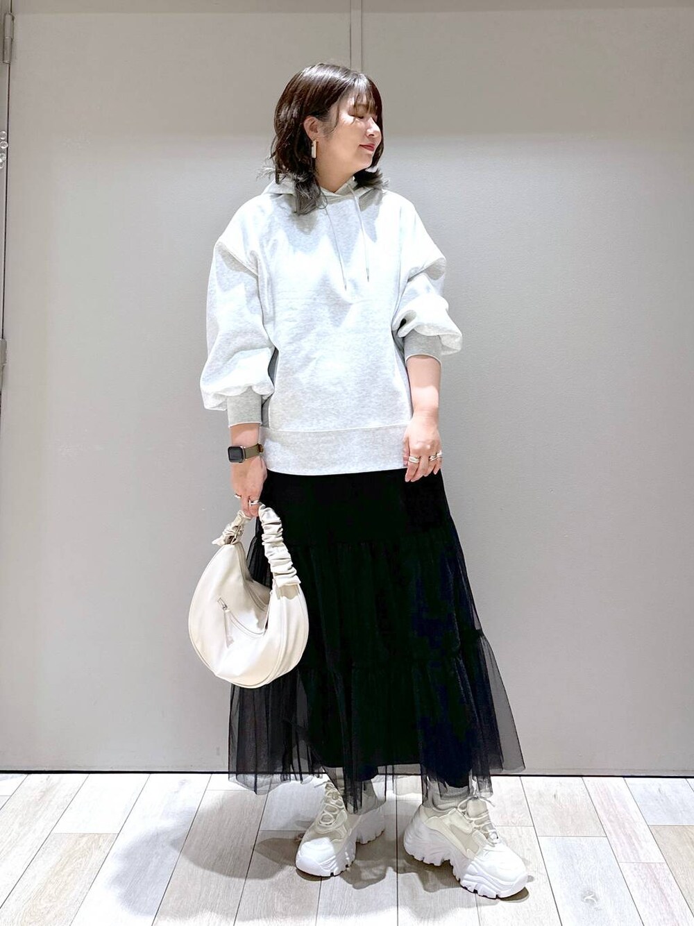 ホワイト系のスニーカー、グレー系のパーカー、ホワイト系のショルダーバッグを着用したレディースの冬コーディネートの1枚目の写真