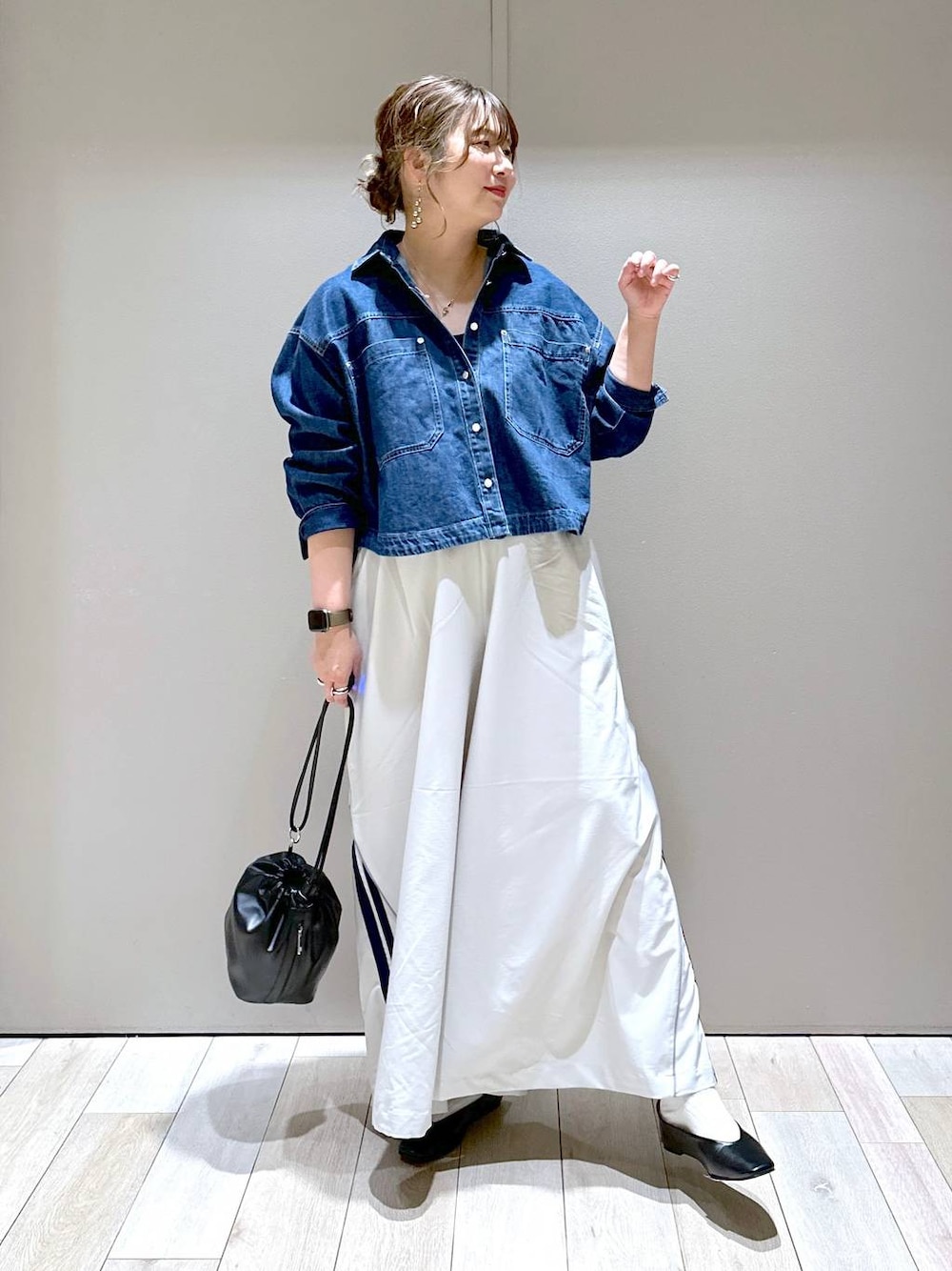 ブラック系のショルダーバッグ、ブラック系のパンプス、ブルー系のシャツ/ブラウスを着用したレディースの春コーディネートの1枚目の写真