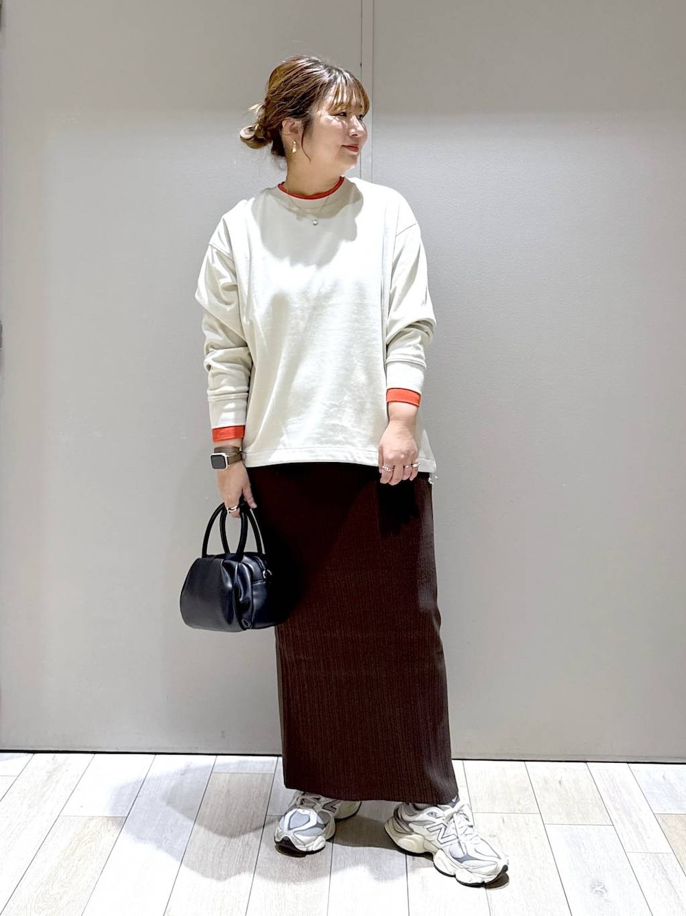 ブラック系のショルダーバッグ、ベージュ系のTシャツ/カットソー、ブラウン系のスカートを着用したレディースの秋コーディネートの1枚目の写真