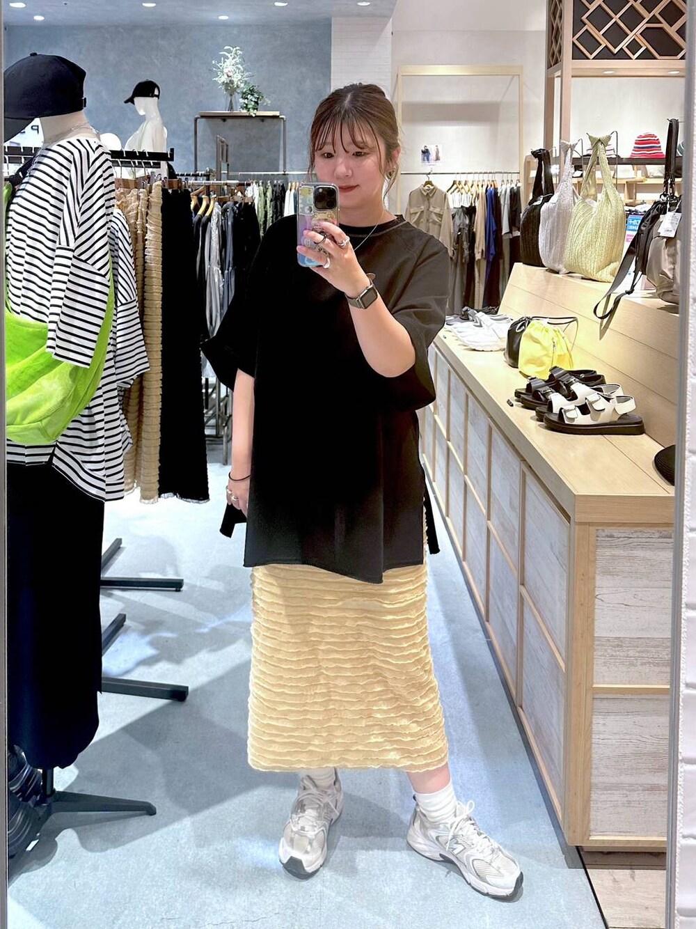 ベージュ系のスカート、ブラック系のTシャツ/カットソーを着用したレディースの春コーディネートの1枚目の写真