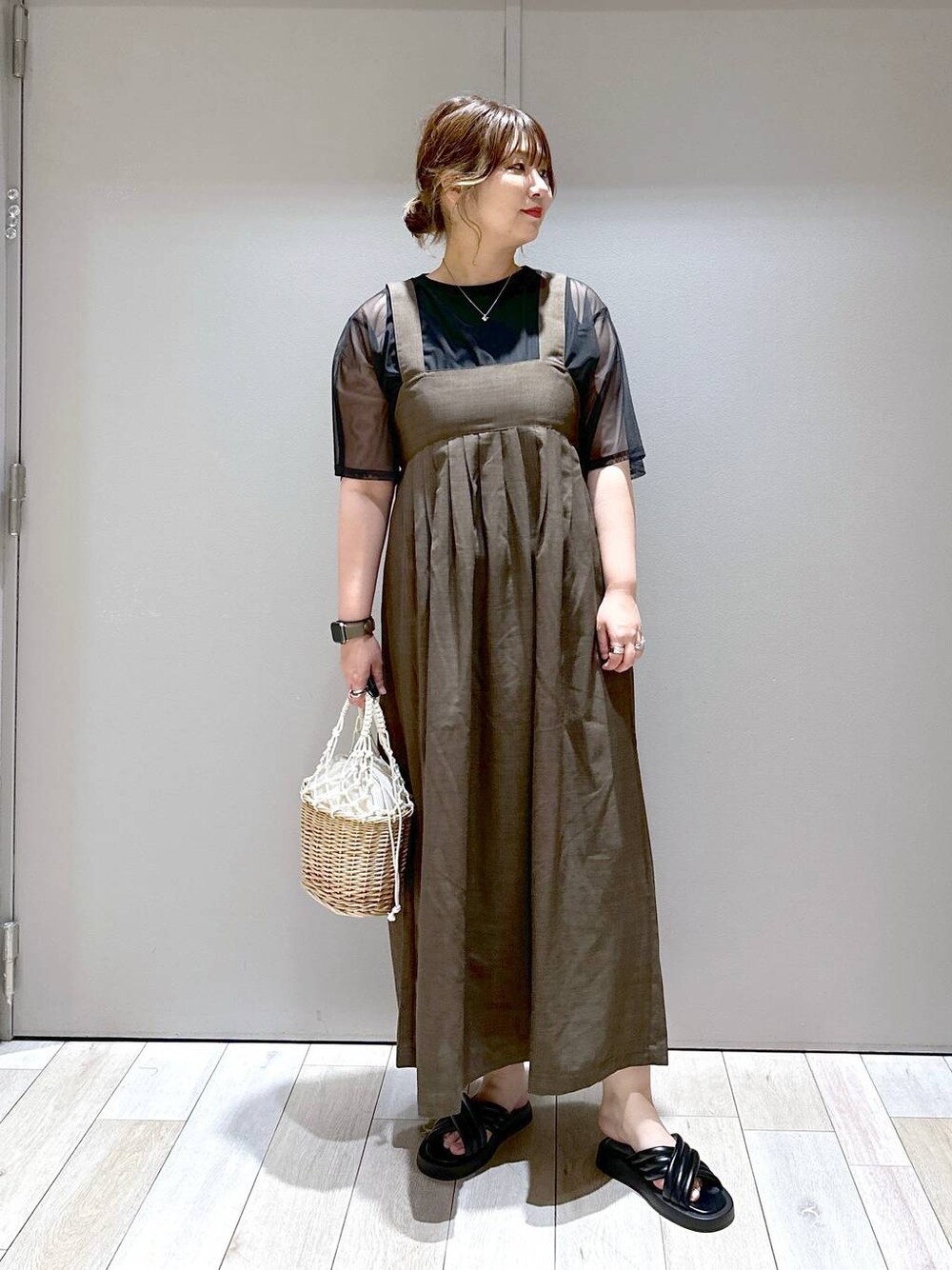 オレンジ系のかごバッグ、ブラック系のTシャツ/カットソー、ブラック系のサンダルを着用したレディースの春コーディネートの1枚目の写真