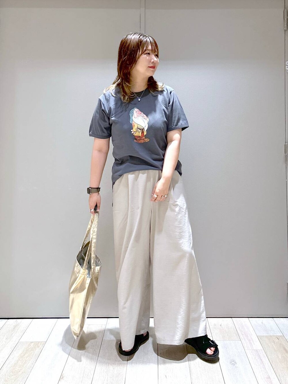 ベージュ系のその他パンツ、ブラック系のサンダル、ゴールド系のトートバッグを着用したレディースの夏コーディネートの1枚目の写真