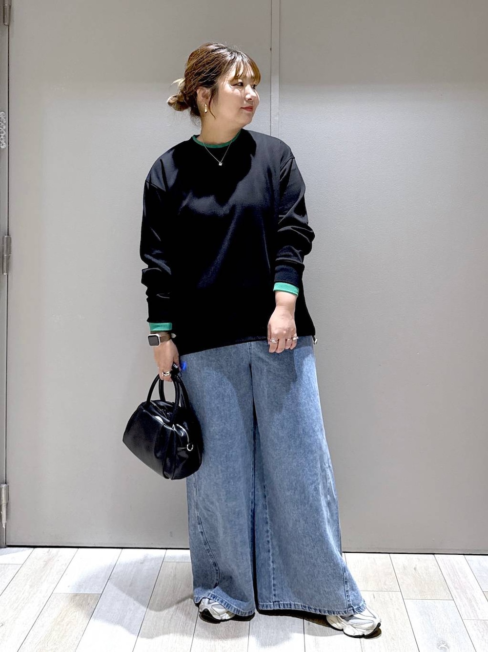 ブラック系のショルダーバッグ、ブラック系のTシャツ/カットソー、ブルー系のデニムパンツを着用したレディースの秋コーディネートの1枚目の写真