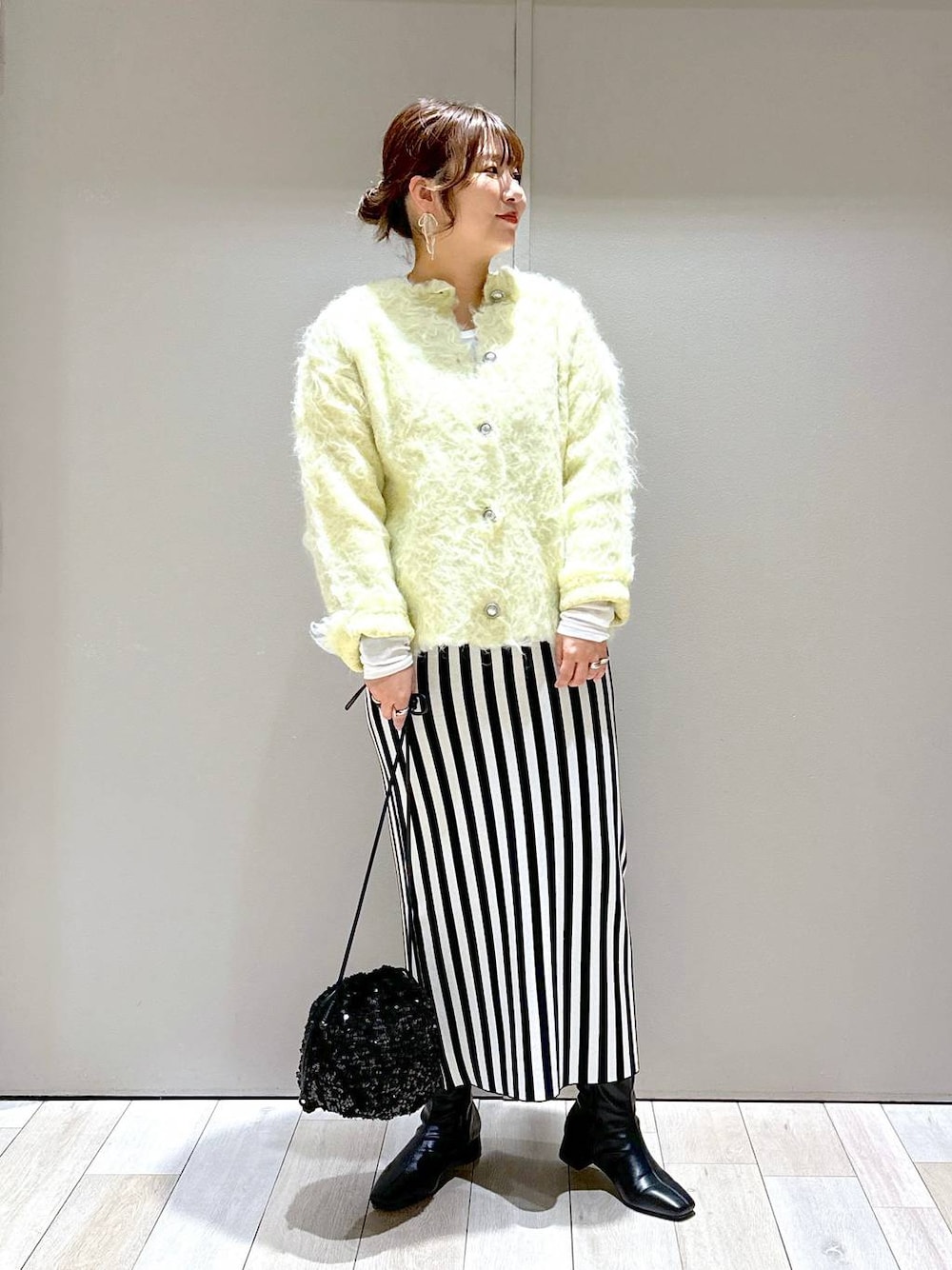 ブラック系のショルダーバッグ、ブラック系のスカート、グリーン系のカーディガン/ボレロを着用したレディースの秋コーディネートの1枚目の写真