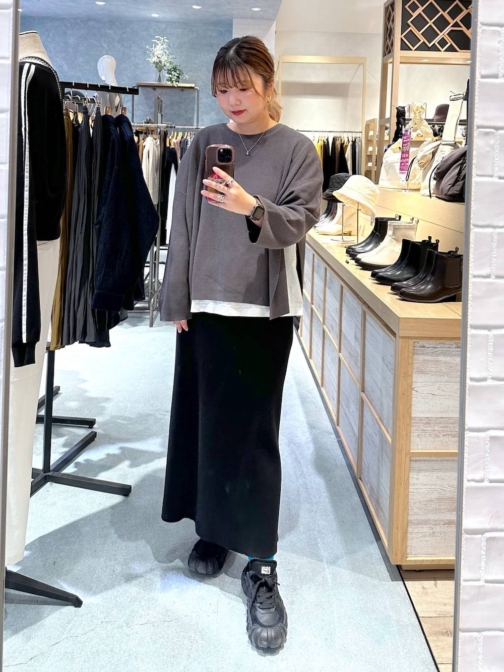 ホワイト系のTシャツ/カットソー、グレー系のニット/セーター、ブラック系のスカートを着用したレディースの秋コーディネートの1枚目の写真