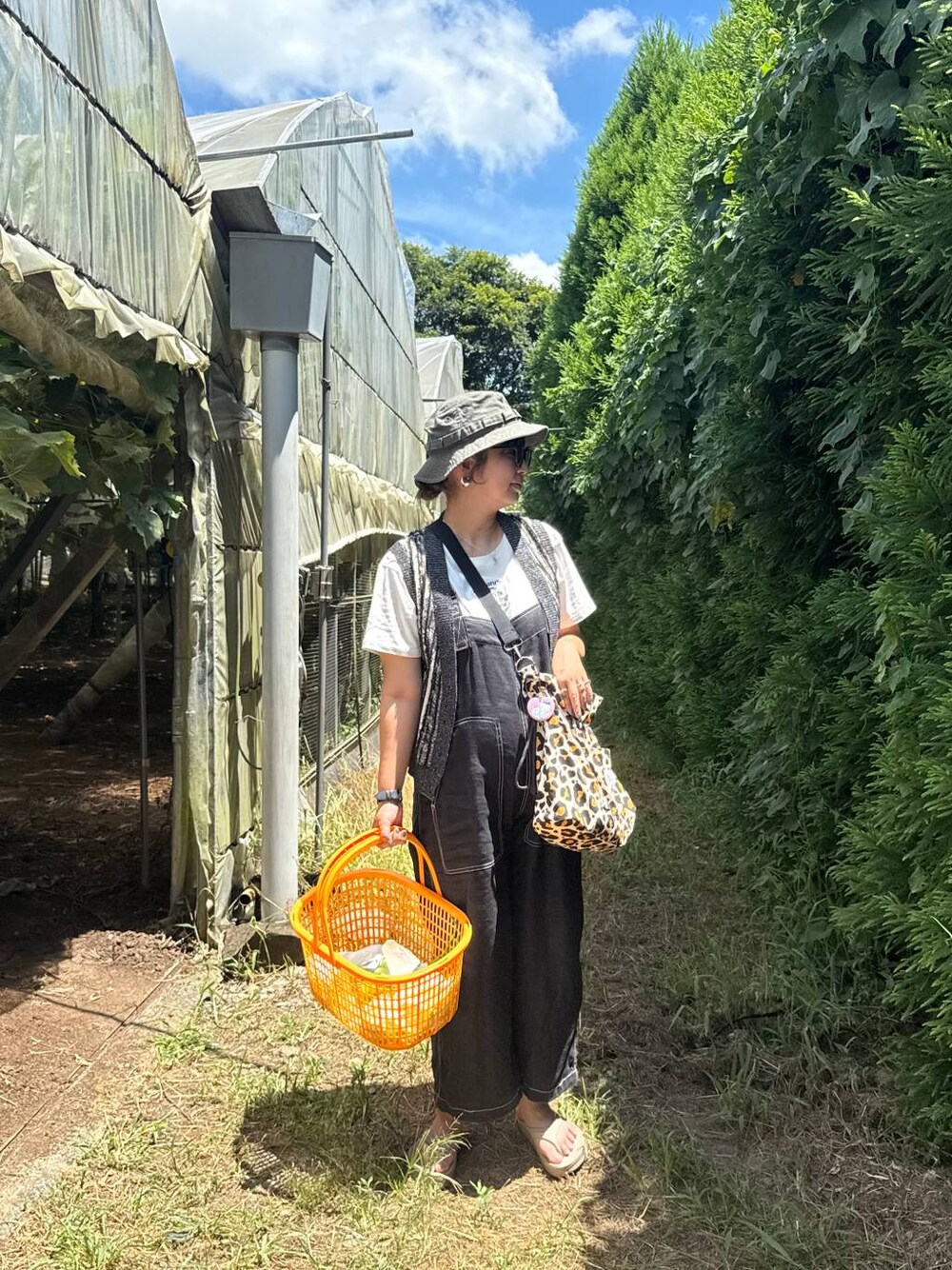 ブラック系のベスト、ホワイト系のTシャツ/カットソー、ベージュ系のサンダルを着用したレディースの夏コーディネートの1枚目の写真