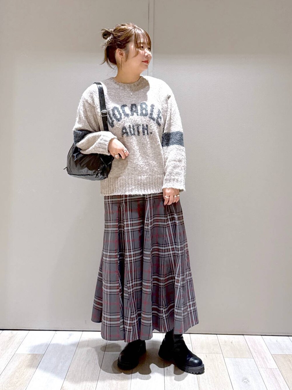 グレー系のスカート、ブラック系のブーツ、ブラック系のショルダーバッグを着用したレディースの冬コーディネートの1枚目の写真