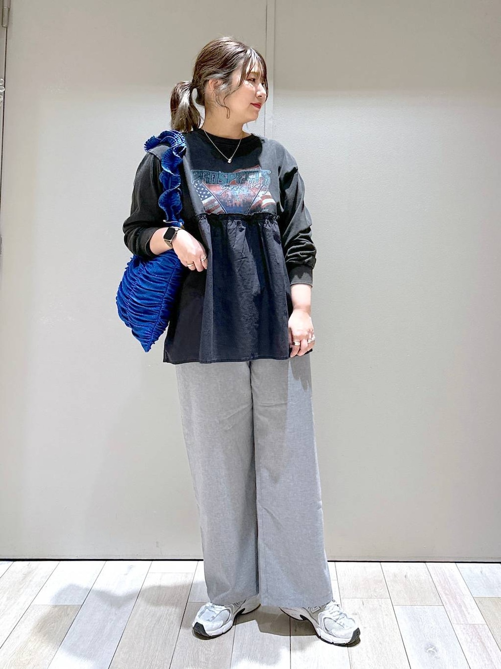 ブルー系のトートバッグ、グレー系のスラックス、グレー系のTシャツ/カットソーを着用したレディースの冬コーディネートの1枚目の写真