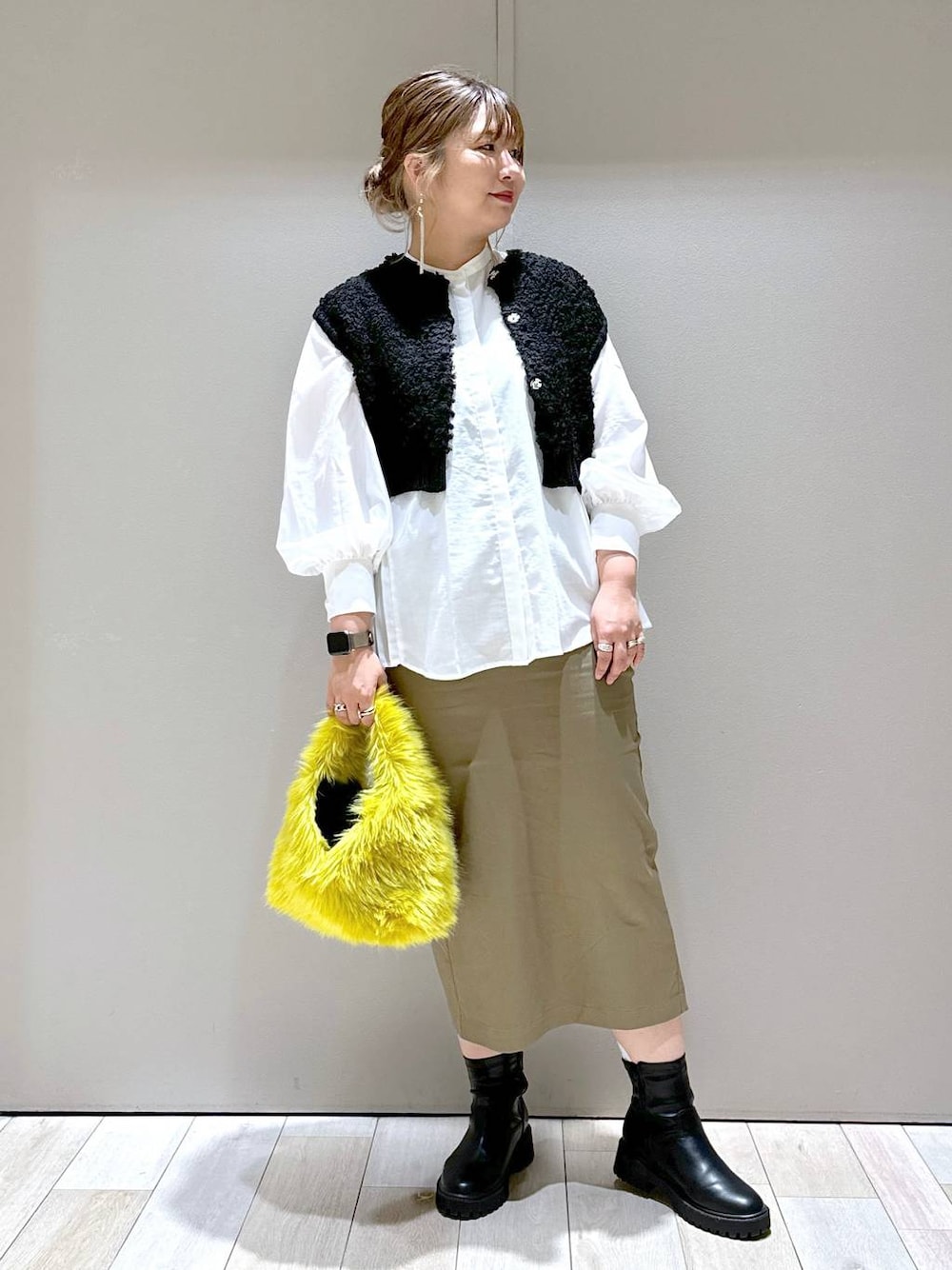 イエロー系のハンドバッグ、ブラック系のブーツ、ホワイト系のシャツ/ブラウスを着用したレディースの秋コーディネートの1枚目の写真