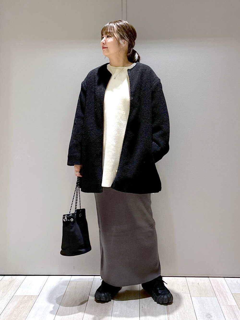 グレー系のスカート、ブラック系のノーカラーコート、ホワイト系のワンピースを着用したレディースの秋コーディネートの1枚目の写真