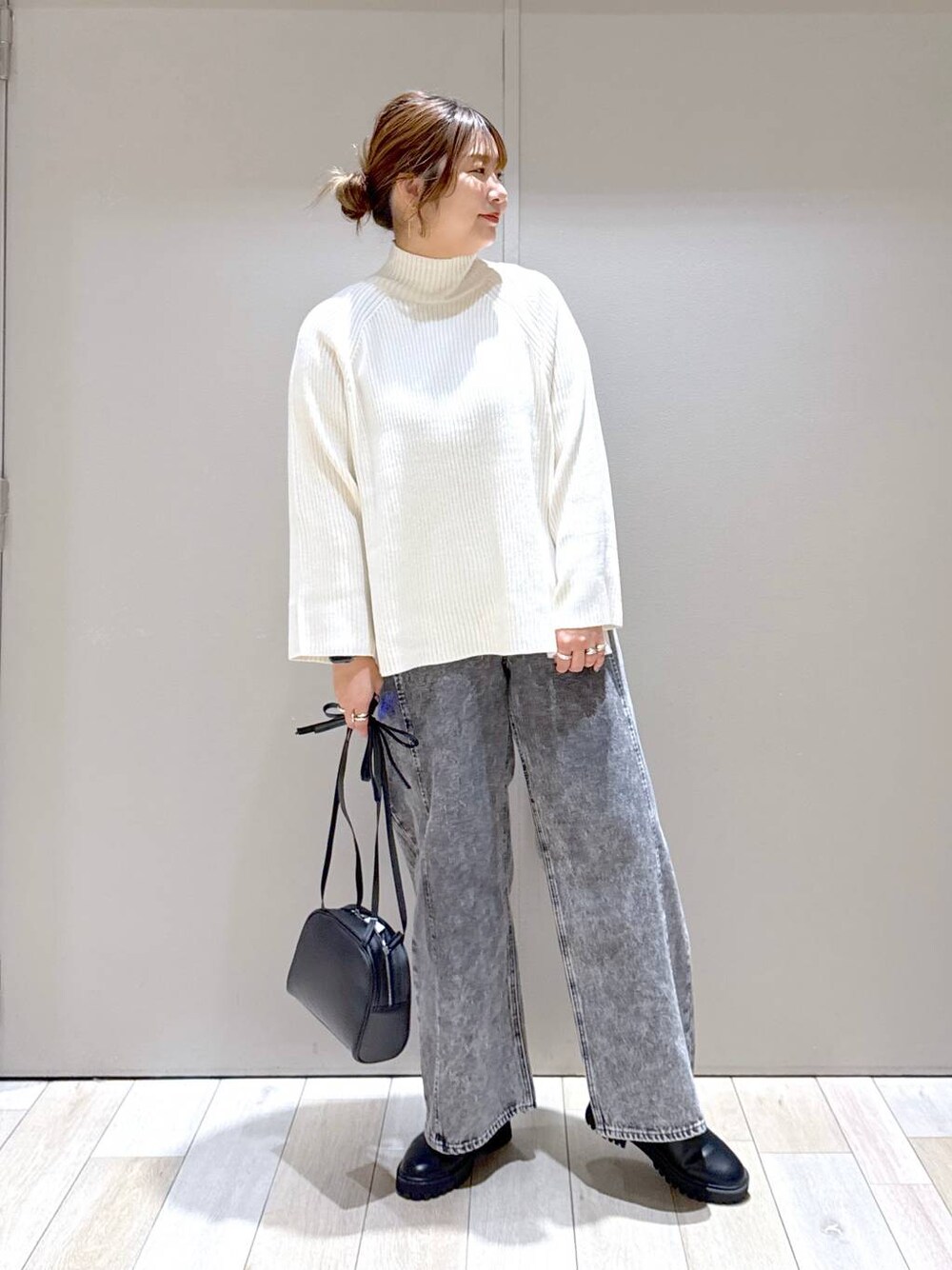 ブラック系のブーツ、ホワイト系のニット/セーター、グレー系のデニムパンツを着用したレディースの冬コーディネートの1枚目の写真